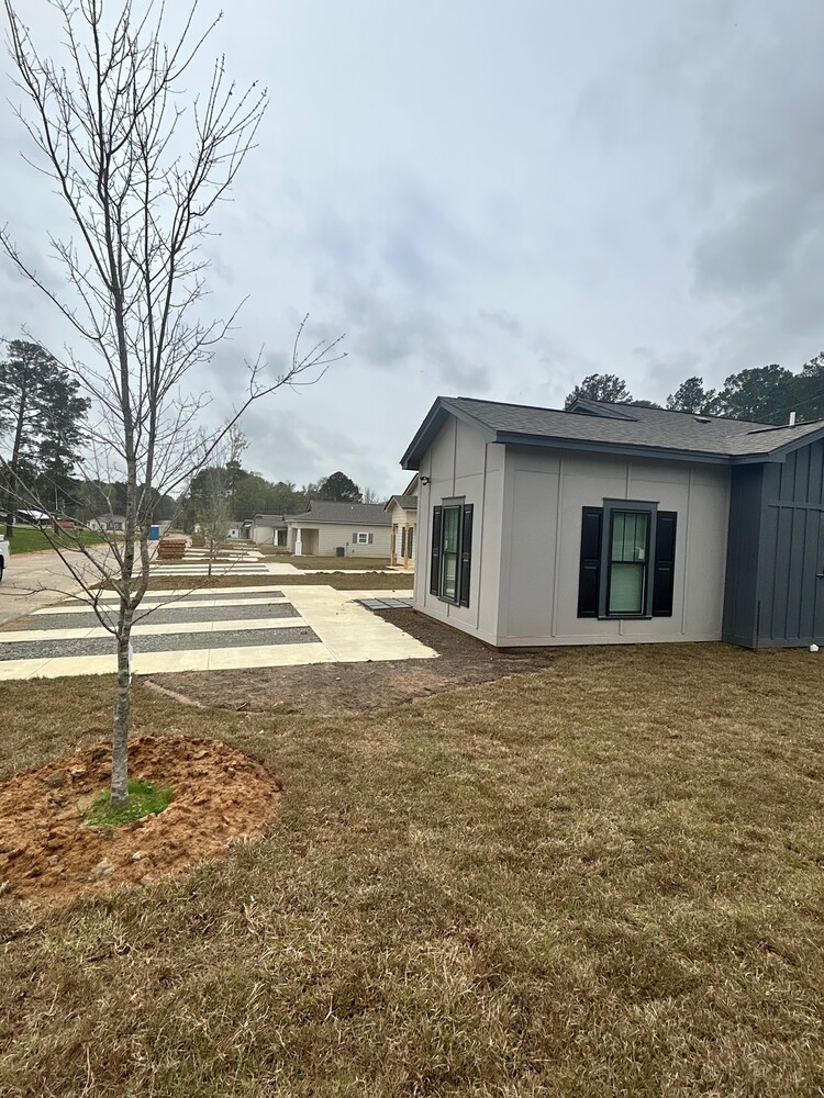 A sidewalk view of a grey house.